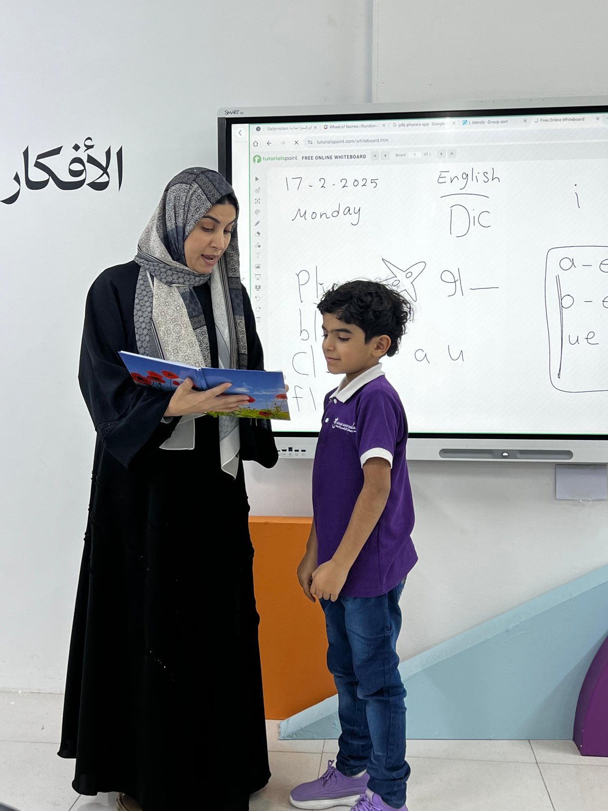 معلمة وطالب أمام السبورة التفاعلية